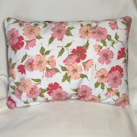 a pink and green floral pillow on a white background