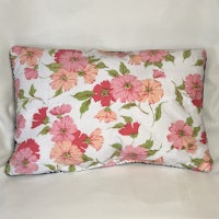 a pink and green floral pillow on a white background